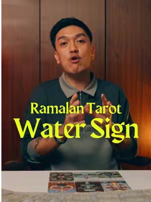 A man with short black hair wearing a black collared shirt is the main subject of the image. He has a direct, inquisitive expression and looks slightly upwards. The text overlay states "Ramalan Tarot Water Sign" in striking yellow font with a blurred outline. Below, a set of tarot cards is partially visible. The background is a warm, reddish-brown, potentially a wood-paneled wall.