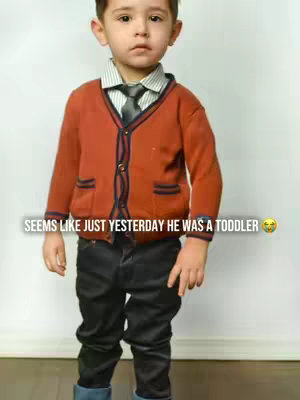 A young boy dressed in a blazer, collared shirt, and tie stands against a plain white background. Text overlays read, "Seems like just yesterday he was a toddler."