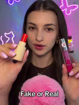 A woman holds up a lipstick and a lip gloss for review. The background has neon lights.