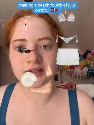 A selfie-style shot features a fair-skinned person with auburn hair. The person is centered in the frame, looking directly at the camera. The person's skin has a slight blush. Overlaid on the image are several decorations. There is a text overlay at the top, and a set of sunglasses is positioned just under the text. Also included on the frame are fashion items that include a bikini, a skirt, and sandals arranged around the person. The background includes a portion of a bedroom with more clothing items.