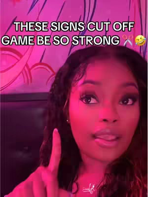 A selfie-style shot featuring a young woman with a close-up focus. She has long, dark hair and is wearing makeup. The background is a magenta-toned setting, with text overlayed in a contrasting color to enhance visibility. The woman is looking towards the camera with a facial expression that suggests she is speaking or making a statement. The lighting seems to be artificial, creating a soft and even glow.