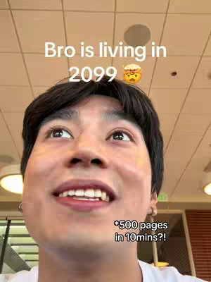 A young man looking up with a surprised expression. Text overlays state 'Bro is living in 2099' with an emoji above his head, and '*500 pages in 10min?!*' at the bottom. The background shows an uncluttered interior possibly a cafeteria.