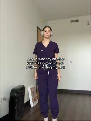 A full-body shot of a person in a purple medical scrub uniform stands in front of a plain background. White text is overlaid on the image, providing context.