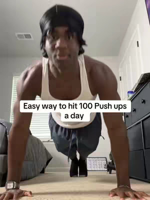 A man in a white tank top and dark blue shorts is shown from the chest down, performing a push-up with his hands on what appears to be a push-up board. The caption is in a white box in the center of the image. The background is a cozy-looking bedroom.