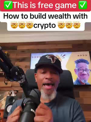 The cover image features a man in a black Atlanta Falcons cap, a black microphone, in front of a wooden wall. The text 'This is free game' and 'How to build wealth with crypto' are overlaid at the top and bottom of the frame in a white font and green check (top). The words 'crypto' uses emoji faces as well. In the background is some form of monitor or wall art and a book, with the man presenting with his hands.
