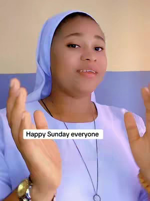 A woman wearing a blue habit and a matching head covering is speaking to the camera with her hands raised, smiling, and looking upward. A white rectangle with the text 'Happy Sunday everyone' is placed at the bottom of the frame.
