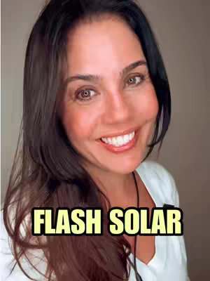 A woman with long, dark hair and fair skin smiles brightly at the camera. She wears a white top and a necklace is visible. The background is a blurred neutral tone with text overlayed in yellow.