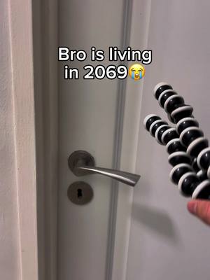 A white door with a metal handle in the center and a black and white flexible tripod angled right. Text is overlayed at the top center.