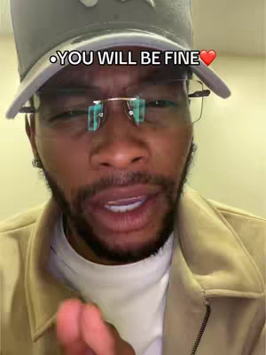 A close-up shot of a man's face fills the frame, with a gray cap on his head. He wears eyeglasses with light green lenses. The text overlay reads, 'YOU WILL BE FINE' in a white font on a black backdrop with a red heart emoji on the right