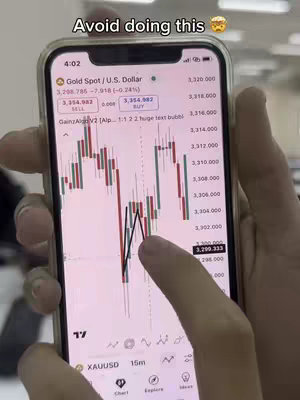 A zoomed-in screenshot from a phone showing a trading chart with candlestick graphs, an overlaid text and a hand touching the screen.