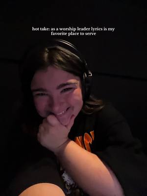 A selfie-style image featuring a young woman with dark hair and headphones, smiling and resting her chin on her hand. Above her is text overlaid on the image.