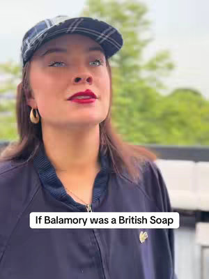 A woman wearing a plaid newsboy cap and a dark zip-up coat, looks upwards with bright eye makeup and red lipstick. Text, in a white rounded rectangle, overlays the bottom of the image.