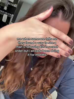 The cover image shows a candid selfie of a person with long, wavy brown hair. Their right hand is raised to cover their face, obscuring their eyes, with the fingers spread slightly. Overlaid on the image is text written in a simple, white font. The background seems to be a domestic setting, partly visible through the opening between the fingers and the side of the head.