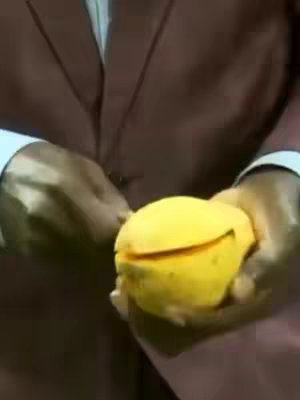 The cover image features a person holding a partially cut, yellow mango. The person is wearing a brown suit. The hands are holding the mango and the background is blurred. The mango has a visible cut, revealing its inside. The lighting appears to be natural or from a soft source. The overall composition focuses on the mango as the central element.