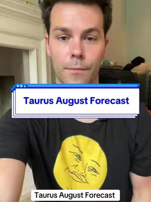 A selfie-style shot of a man centered in the frame. He's wearing a black t-shirt with a yellow graphic, a smiling sun face. Overlayed across the top of the frame is a blue and white text box that says "Taurus August Forecast". Below the overlay is another shorter white text box also saying "Taurus August Forecast". He is in what looks like a home setting, with part of a door frame visible in the background.