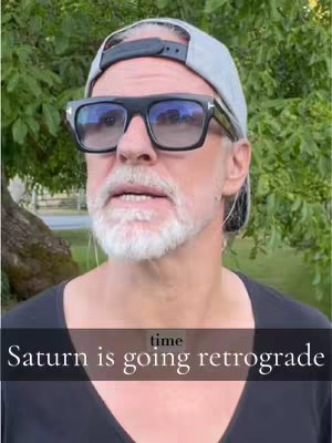 A man with a grey cap and sunglasses is facing the camera, set against a blurred green background. Text overlay in the center of the bottom is: Saturn is going retrograde