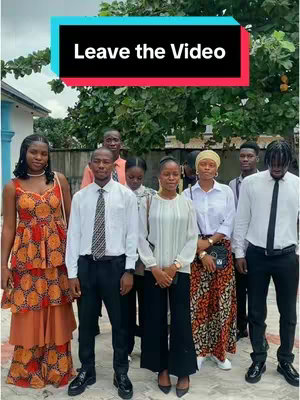A group of nine people, likely young adults, are posing for a photo outdoors. They are dressed in semi-formal attire, with most wearing button-down shirts and ties, one with an orange patterned dress. A text overlay at the top reads 'Leave the Video'.