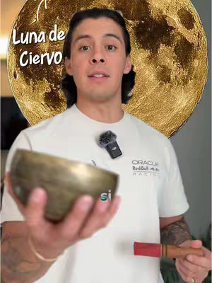 A man is holding a singing bowl, with a microphone pinned to his shirt and a gold moon in the background. Text overlay on the top left says 'Luna de Ciervo'.