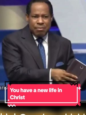 A man in a dark suit is shown in a medium shot, facing the camera with a serious expression. The background suggests an indoor setting with a blue tone. A red rectangular text overlay at the bottom reads: "You have a new life in Christ."