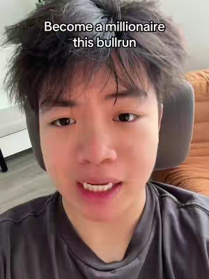 A close-up shot of a young man speaking directly to the camera. He has short, dark, messy hair. Above him, a text overlay reads 'Become a millionaire this bullrun'. Behind him is a neutral-colored chair and a brown, textured surface suggesting a couch or wall.