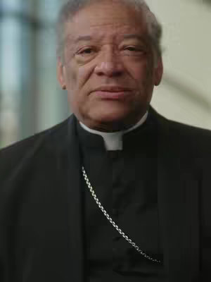 The cover image features a medium shot of a man, presumably Bishop Joseph Perry, against a somewhat out-of-focus background. He is wearing a black suit, a white clerical collar, and a silver chain. The man has short, graying hair and a serious facial expression.