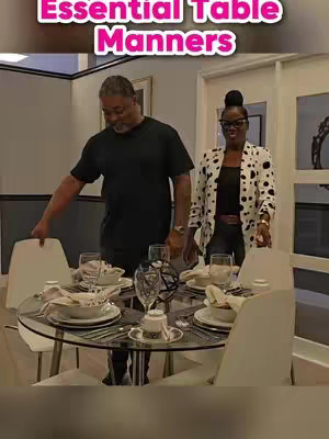 Image shows a man pulling out a dining chair for a lady, setting up a table for a meal. The scene is set in a formal dining room with a round table and silverware.