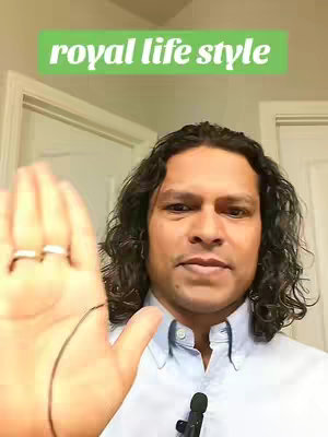 A person with curly dark hair stands in front of a plain background, holding out an open hand with a focus on the palm. The person is wearing a light blue button-down shirt and has a stern look. A green rectangular text overlay at the top says, 'royal life style'. Adjacent to the person is a microphone.