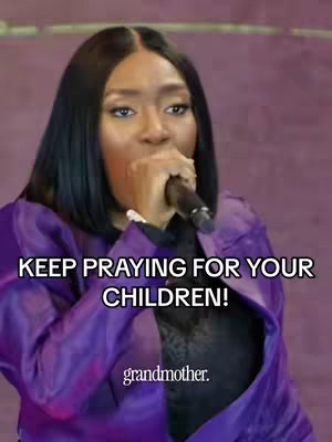 A vertical video cover image featuring a woman with dark hair, holding a microphone and speaking. She's wearing a purple blazer over a black top. The image has a purple background, giving the impression of a stage or presentation setting. Overlayed text at the bottom reads "grandmother."