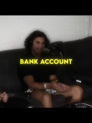 The cover image shows a man sitting on a black couch, with a microphone in front of him. The text overlayed on the image reads 'BANK ACCOUNT'. The man is wearing a black shirt and has a bracelet on his wrist. His legs are crossed, and he is making a hand gesture.