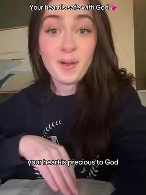 A young woman with long brown hair is centered, looking towards the viewer with a soft expression. Above her head, text overlays announce a positive message. Her attire consists of a dark sweater and in the background, a hint of a room is suggesting an interior shot. The photo is naturally lit, offering a candid and intimate feel.