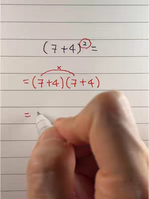 A hand in the lower right corner writes on a piece of lined paper. Equations are written in black and red ink.