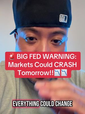 The cover image features a man in a close-up shot, primarily focusing on his face from the eyes down. He is wearing a black cap and a gray t-shirt. The image has two text overlays. The first one is a red rectangle that has a lightning symbol, and the text reads: 'BIG FED WARNING: Markets Could CRASH Tomorrow!!📉📉' The second text overlay, is a dark rectangle at the bottom with the text saying: 'EVERYTHING COULD CHANGE.'