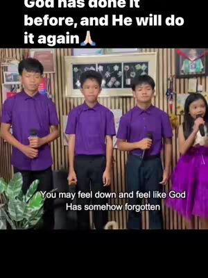 The image showcases a group of four young people, likely a gospel choir, standing in front of a vertical striped wooden backdrop. Three of the individuals are young men dressed in purple dress shirts, each holding a microphone in their right hand. The fourth person is a young woman in a purple dress and has a microphone in her left hand. The video's text overlay is near the top, and another text shows how the viewers may be feeling, at the bottom.