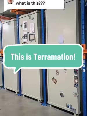 The image shows an interior shot of a facility. In the background are several large, tall, beige-colored cabinets or units, likely for storage. In the foreground, a speech bubble overlayed with the words "This is Terramation!" is positioned in the lower portion of the image. Small items like photographs are placed on the cabinets. The lighting appears functional, suggesting an industrial setting.