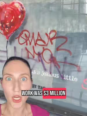 A woman with wide eyes and an open mouth is in the foreground. Behind her, a red heart balloon is partially visible. In the background, there is visible street art with red coloring.