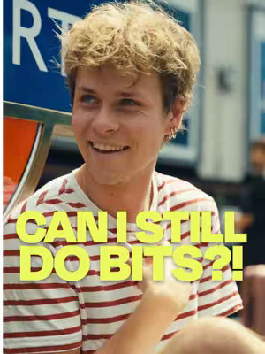 A young man with light hair and a striped shirt smiles directly at the camera. Bright yellow text overlayed on the image asks 'Can I Still Do Bits?!' The background appears to be a blurry outdoor scene.