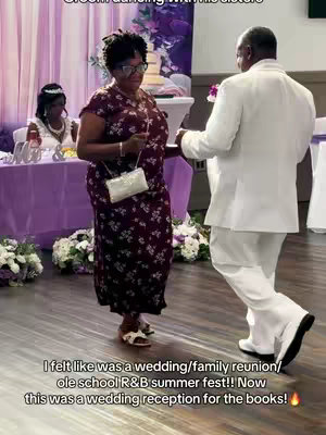 The image shows a wedding reception scene featuring a smiling Black woman in a floral dress dancing with a man in a white suit. The woman holds a purse, and they are on a dance floor with floral decorations and tables.