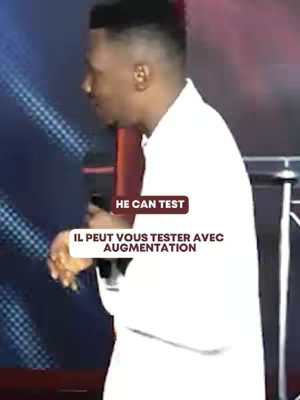 A man with short dark hair wearing a white shirt is standing on a stage with a microphone in his hand talking to the audience, with text overlays. Dark backdrop.