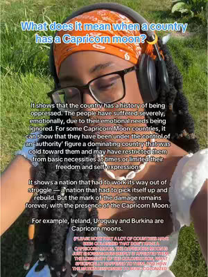 A selfie-style photo of a woman with large-framed glasses, headphones, and an orange bandana. The background appears to be a grassy area. Text overlays the image.