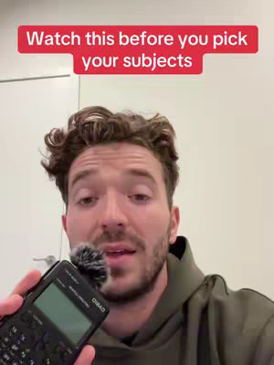 A man is holding a calculator with a microphone attached.  Text in a red banner overlays him.