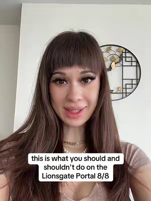 A woman with long, dark brown hair and bangs looks directly at the camera, while in front of her is a black and gold decoration and a plain white wall. At the bottom of the frame, overlaid text appears in a rectangular box.