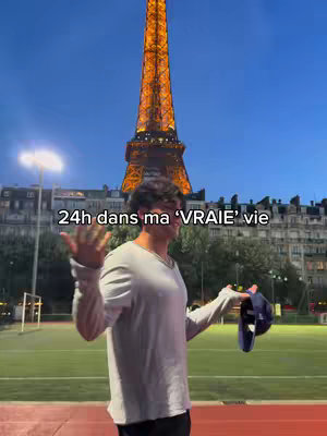 A man stands in front of the Eiffel Tower at dusk, holding a hat. Text overlayed on the image reads '24h dans ma "VRAIE" vie'. The background features a sports field and city buildings, with the sky transitioning to night.