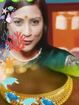 A woman is centered in the frame, looking towards the left while smiling slightly. Her face is the main focus, with a small orange bindi dot on her forehead. She wears a green top and a gold necklace. Overlaid on the image are playful graphics: starfish, seashells, and coral. The bottom of the image features a golden jeweled necklace and some animated blue fish and turtles.