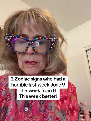 A close-up shot of an older woman wearing large, embellished glasses. She has light-colored hair and is wearing a patterned pink top. A text overlay at the bottom states that the content is about 2 Zodiac signs who had a horrible last week, June 9, followed by a message of hope.