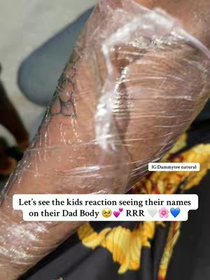 An arm with a partially visible tattoo is wrapped in clear plastic wrap. The wrap has a few wrinkles and imperfections, but it's overall transparent, revealing the skin underneath. The arm is placed against a background with a yellow and orange floral pattern.
