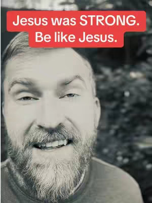 A black and white close-up shot of a man with a beard smiling at the camera. Text overlay in a red bar at the top reads, 'Jesus was STRONG. Be like Jesus'.