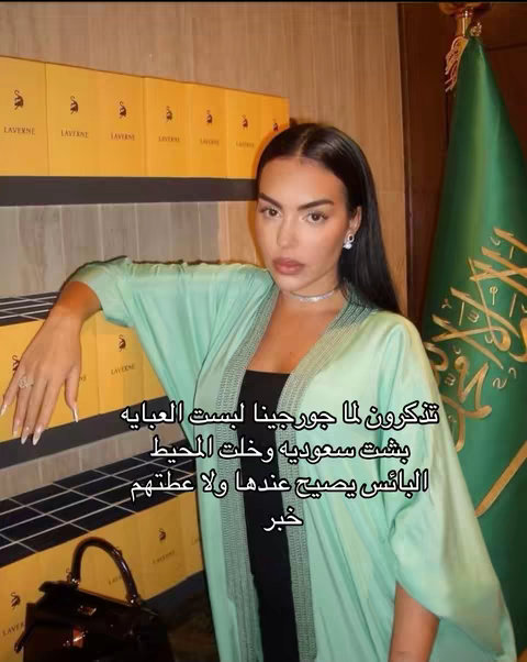 A woman in a light green robe with text overlay, in front of shelves of luxurious items and a flag. The composition is balanced, with the woman as the focal point.