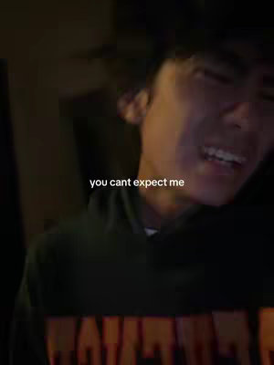 A close-up shot of a young man with dark hair and a green hoodie intensely looking towards the right of the frame. His mouth is open, showing his teeth, and his expression suggests strong emotion. White text overlayed across the bottom reads 'you can't expect me'. The background is dark and blurry.