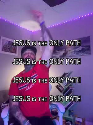 The image shows a man in a room. He is wearing a red shirt and a black cap and there is a tattoo on his left arm. The room has a painting in the background behind him. Text overlays of 'JESUS IS THE ONLY PATH' are repeated in the image.