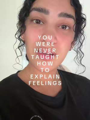 A medium shot of a person's face, with text overlayed. The person has curly dark hair, a black top, and is looking towards the camera. Overlaid in the middle of the screen is white text.